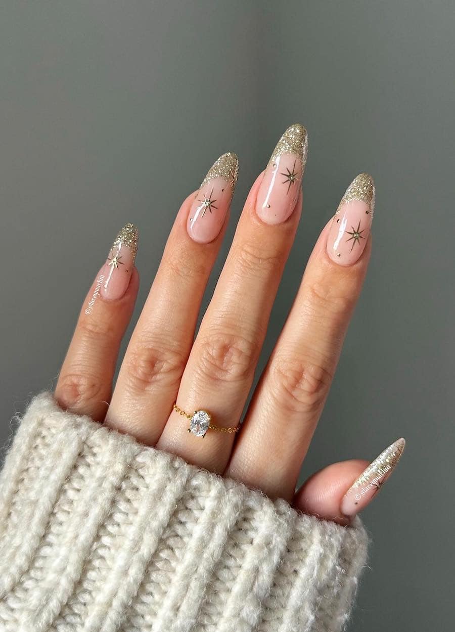 long nude nails with gold glitter tips and star accents