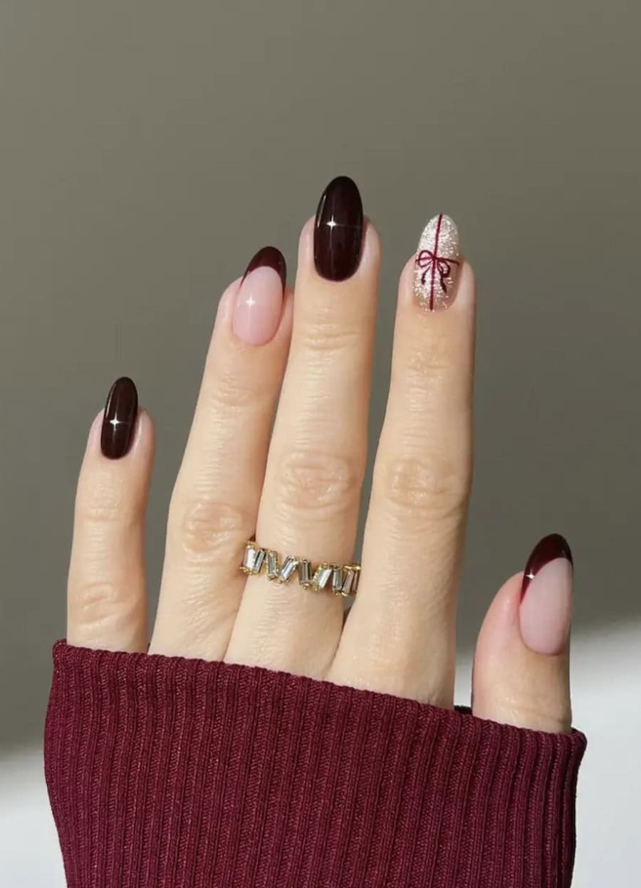 gold glitter and burgundy nails with a present accent nail