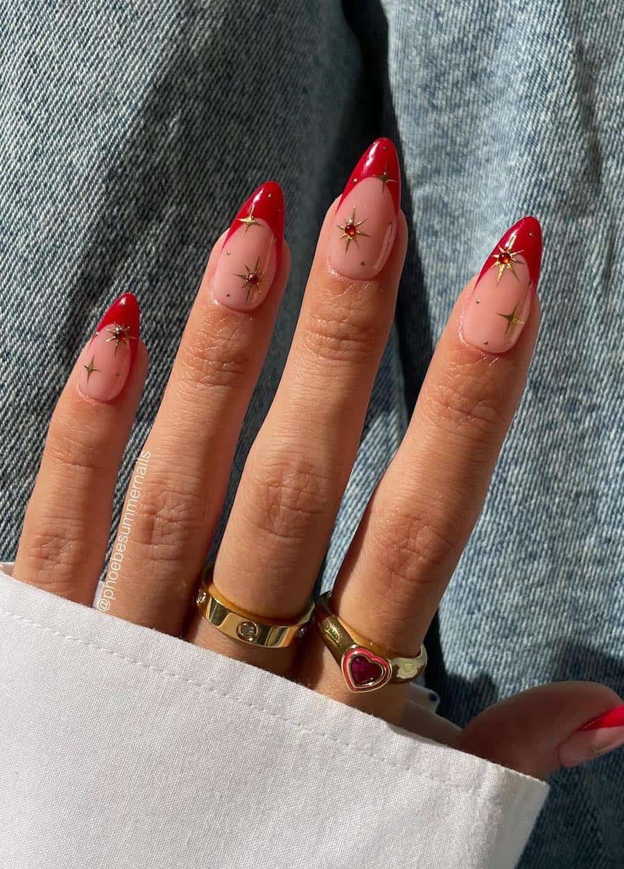 nude nails with red french tips and gold star accents