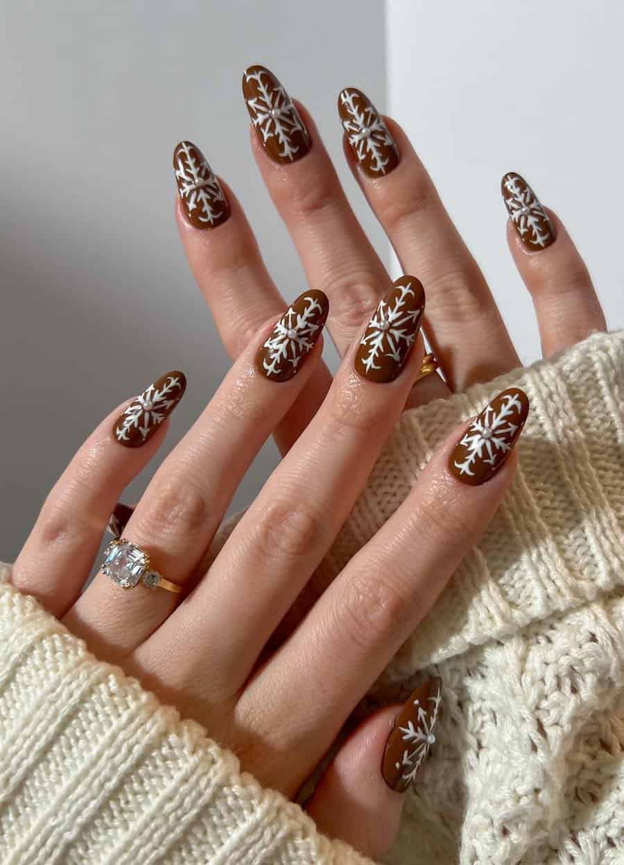 brown nails with white snowflakes and pearl centers