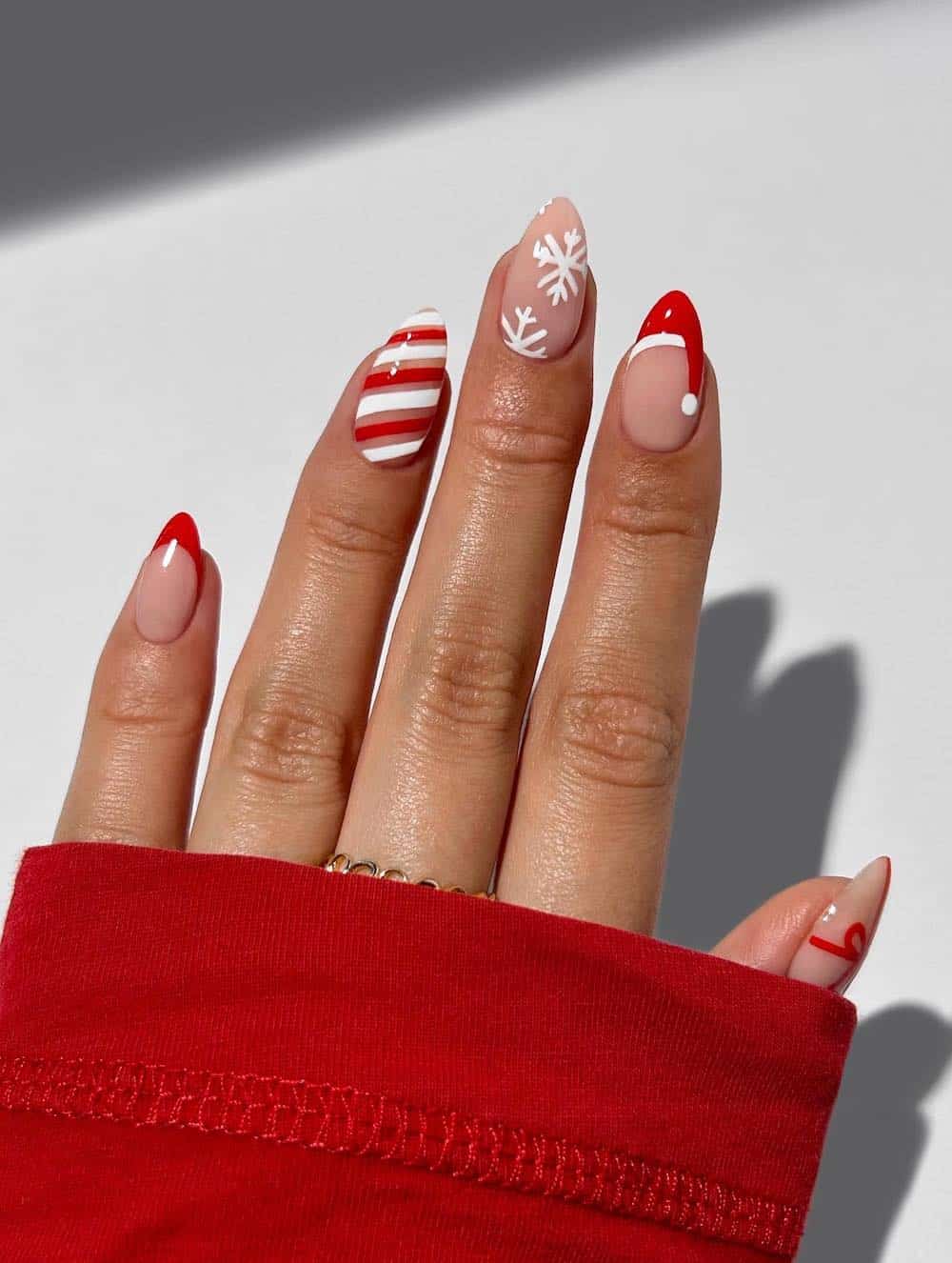 red and white christmas nails with candy cane art, snowflakes and a santa hat
