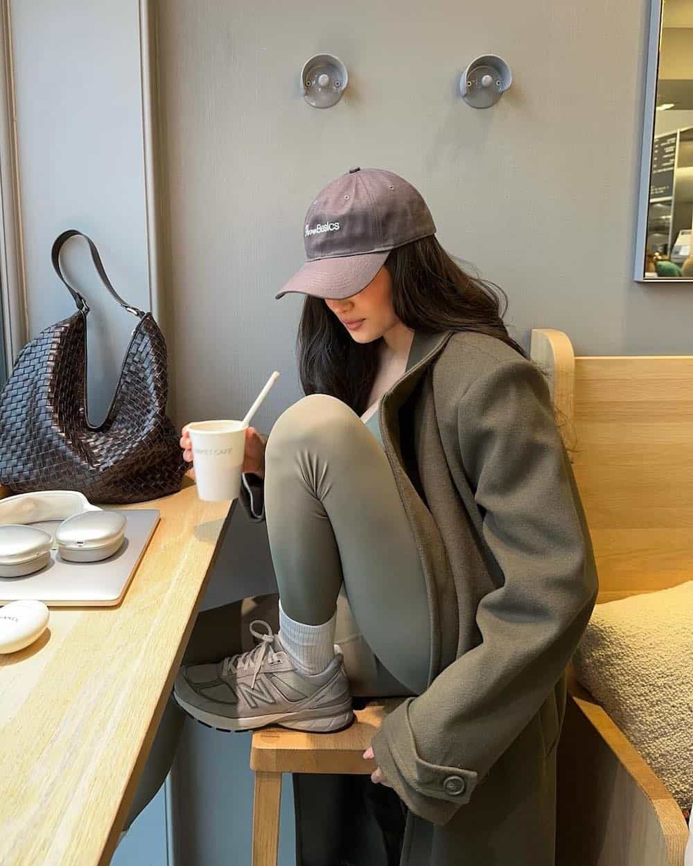 Woman wearing leggings and a wool coat with New Balance sneakers.