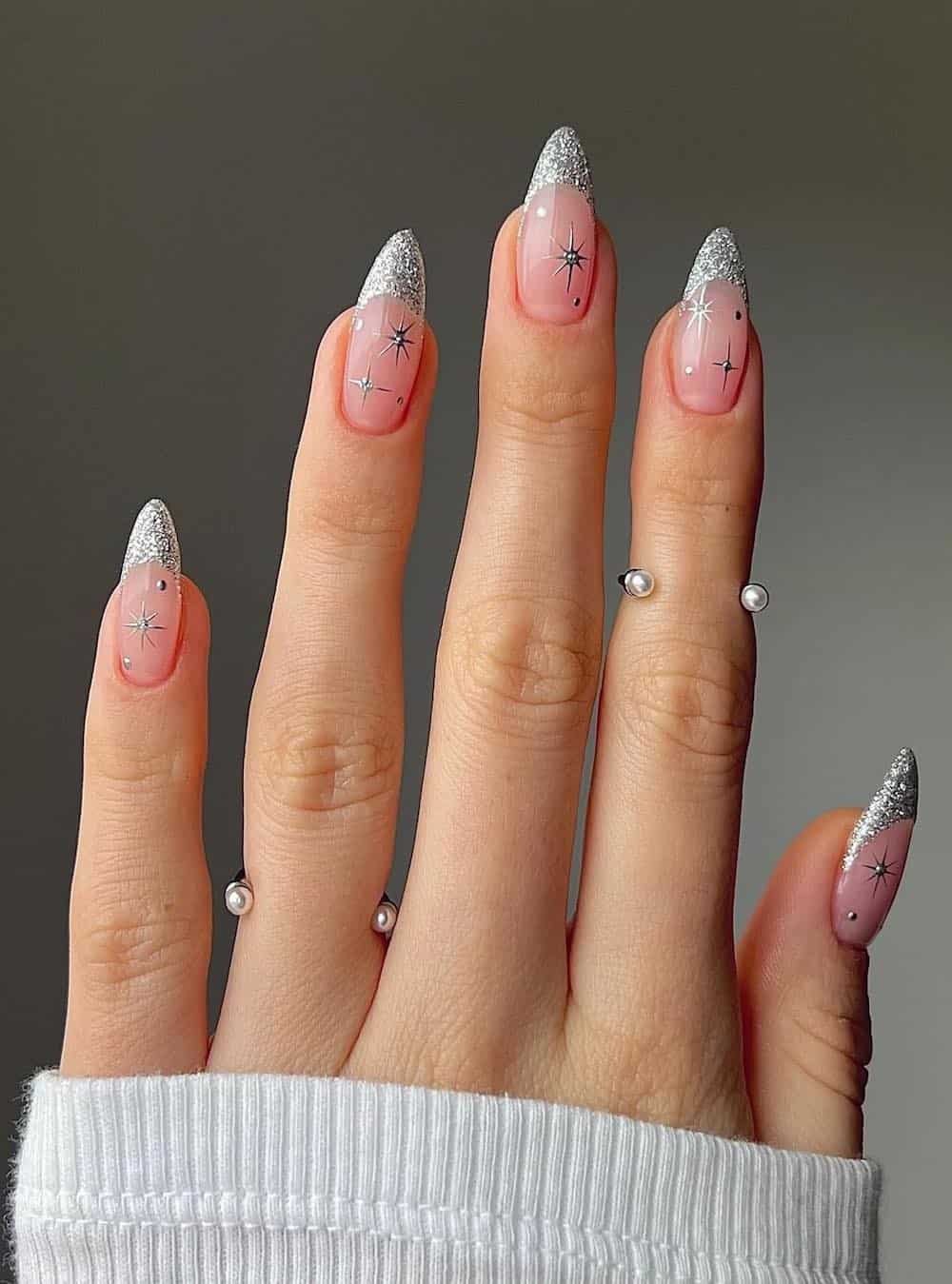 Long nude pink almond nails with shiny silver tips and glitter